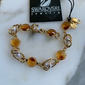 Swarovski bracelet with pearl, amber and gold color details.